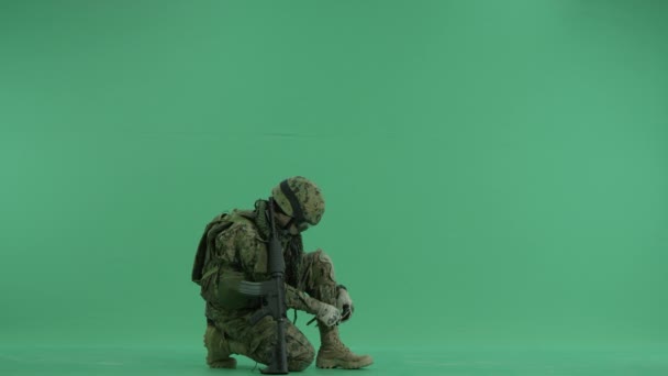 Soldat bindet Schnürsenkel an grünen Bildschirm — Stockvideo
