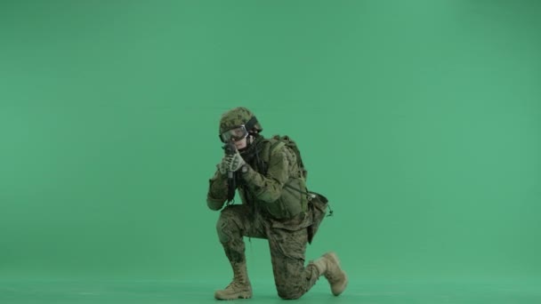 Soldier sitting and targeting at camera at green screen — Stock Video