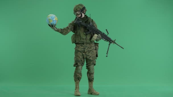 Солдат держит шар и смотрит в камеру на зеленый экран — стоковое видео