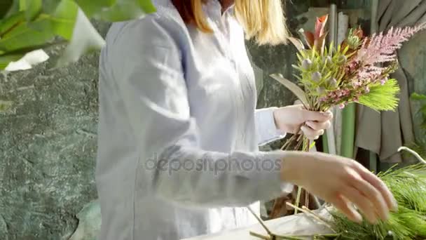Усміхнений жіночий флорист організовує букетик у квітковому магазині — стокове відео