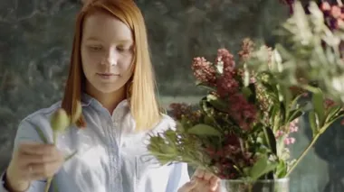 gülümseyen çiçekçi buket cam vazoda düzenlenmesi