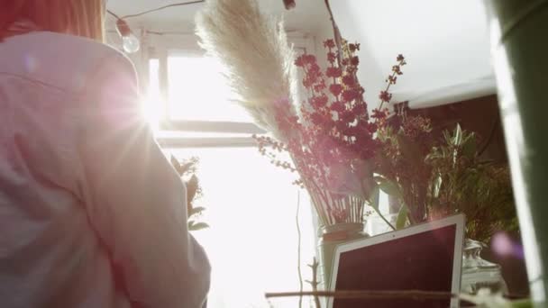 Vista ensolarada de florista arranjando cacho de flores perto da janela — Vídeo de Stock