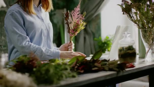 Ingwerfloristin arrangiert Blumenstrauß und arbeitet mit Laptop — Stockvideo