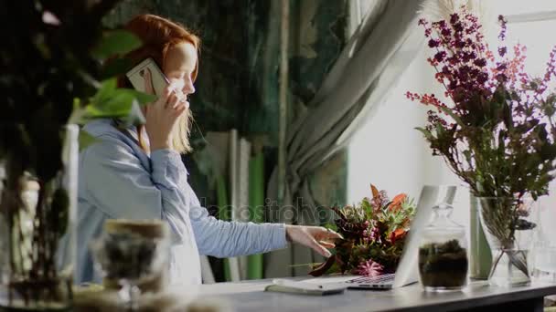 Florista arranjar um monte de flores e falar ao telefone — Vídeo de Stock