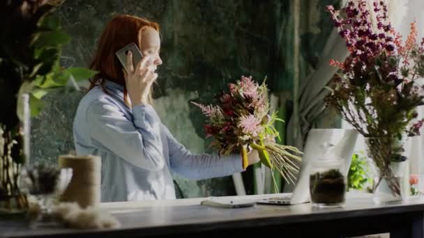 Bloemist holding bos bloemen en praten over de telefoon — Stockvideo