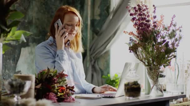 Fleuriste dactylographier sur ordinateur portable parler au téléphone et prendre des notes — Video