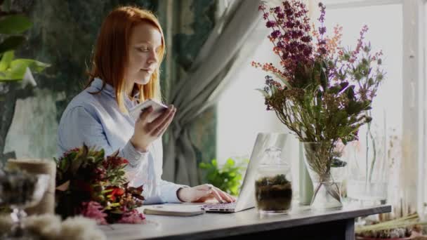 Florista digitação trabalhando com telefone laptop e notas — Vídeo de Stock