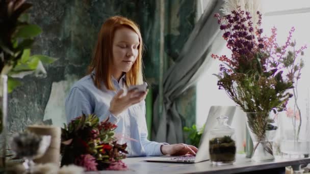 Floristería que trabaja con el ordenador portátil y el teléfono — Vídeo de stock