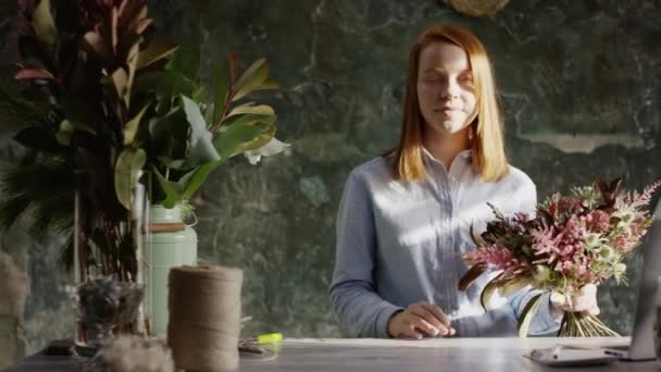 Bloemist samenstellen van bloemen en lookingat camera — Stockvideo