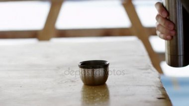 bir termos sıcak çay dökülen adam