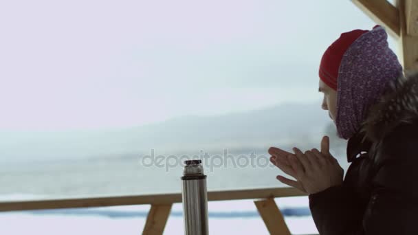 Man drinking tea from a thermos at winter lake view — Stock Video