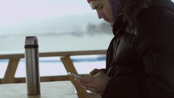Man att skriva ett meddelande på en telefon på vinterförvaring utomhus — Stockvideo
