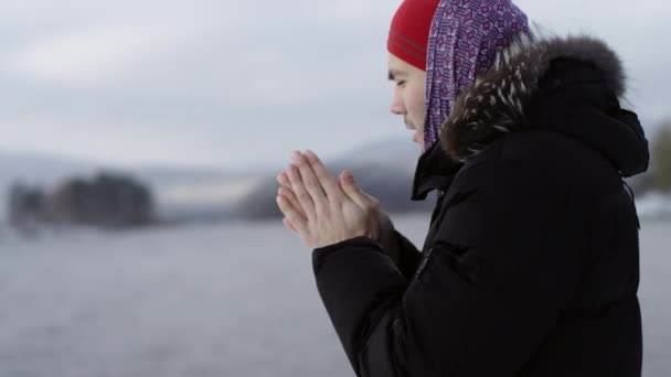 Man värmer händerna nära vintern lake — Stockvideo