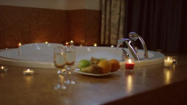 Water stroomt in bad en bord met fruit en champagne glazen — Stockvideo