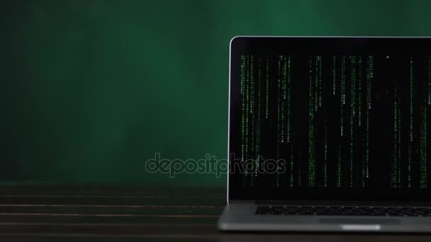 Blick auf den halben Laptop am Schreibtisch mit vertikalem Binärcode — Stockvideo