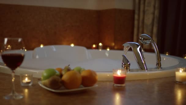 Verres de vin rouge et assiette avec des fruits debout près du jacuzzi , — Video