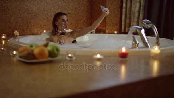 Femme avec du vin rouge dans le bain avec de la mousse prendre selfie — Video