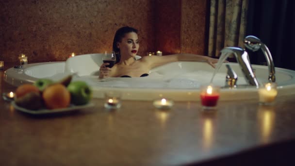 Woman with red wine in bath with foam — Stock Video