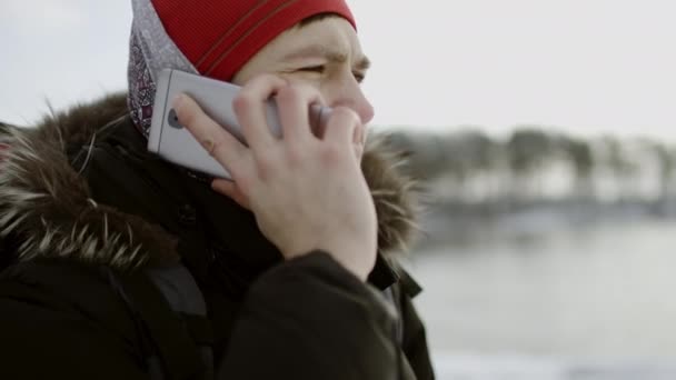 Vrolijke reiziger praten over telefoon een kijken naar winter lake — Stockvideo