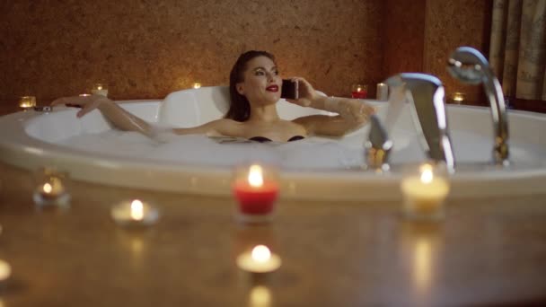 Woman in bath with foam talking on phone — Stock Video