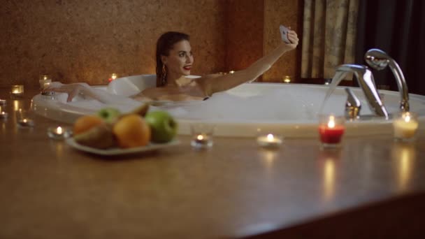 Kvinnan tar selfie i badet med skum i romantisk atmosfär — Stockvideo