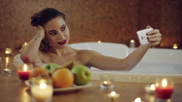 Kvinna poserar på huvudet på kameran i badet med skum — Stockvideo