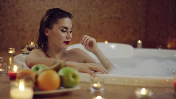 Belle femme prenant une coupe de champagne de petit ami dans le bain — Video