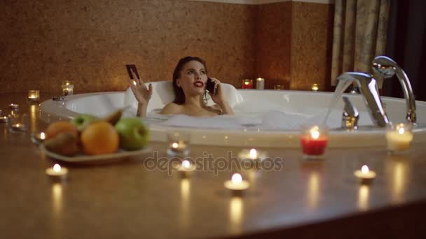 Femme dans le bain parlant au téléphone et tenant la carte bancaire . — Video