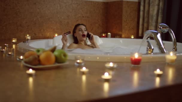 Kobieta w kąpieli rozmowy na telefon i przytrzymanie karty bankowej i uśmiech. — Wideo stockowe