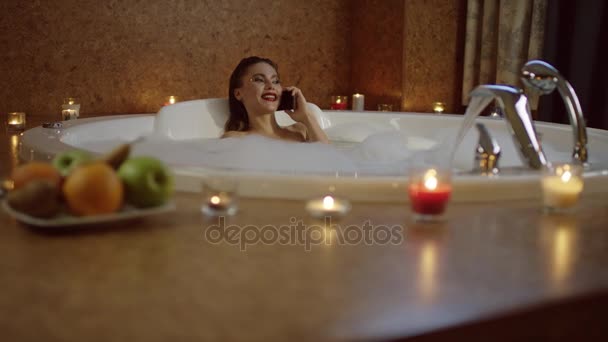 Defocused view of sexy woman taking bath and talking on phone — Stock Video