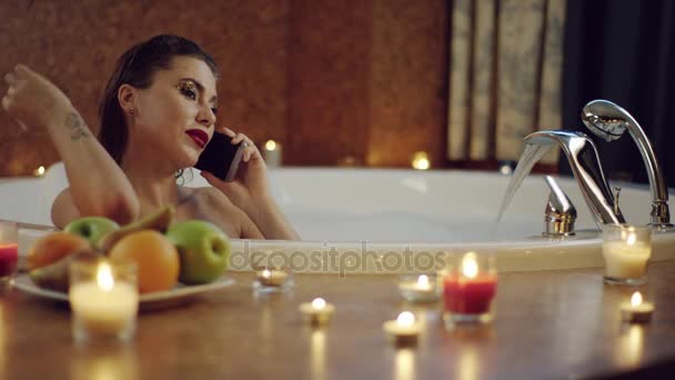 Žena v jacuzzi s pěnou mluvit na telefonu na romantickou atmosféru — Stock video