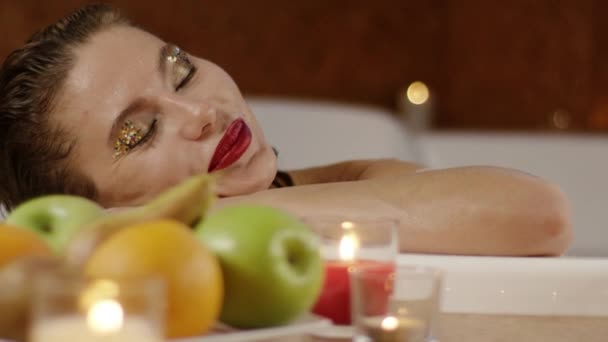 Primi piani di bella faccia femminile rilassante in bagno sullo sfondo di frutti — Video Stock