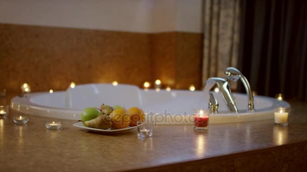 Вид на тарілку з фруктами, що стоять біля джакузі у ванній — стокове відео