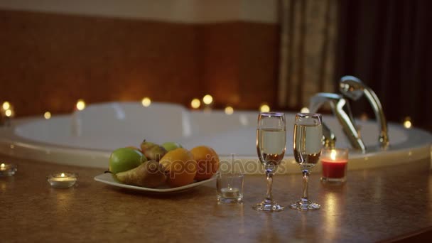 Glazen champagne en plaat met vruchten permanent in de badkamer — Stockvideo