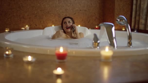 Belle femme parlant par téléphone portable et secouant une carte assise dans le bain — Video