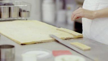 Kadın tek küçük parça hamur eşit parçalar kesip büyük bir parça üzerine koyar.