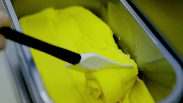 Machine spills yellow ice-cream and woman hand aligns it — Stock Video