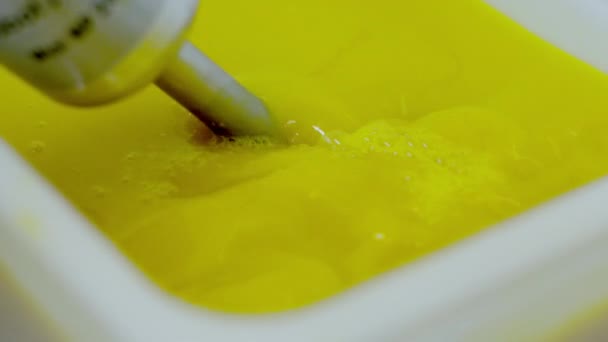 Vrouw hand mengt de vloeistof van de gele kleur — Stockvideo