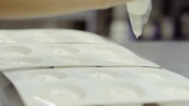 Kadın pişirme çanağı beyaz krema ile doldurur.