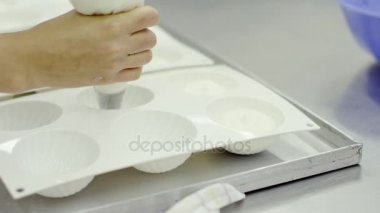 Kadın pişirme çanağı beyaz krema ile doldurur.