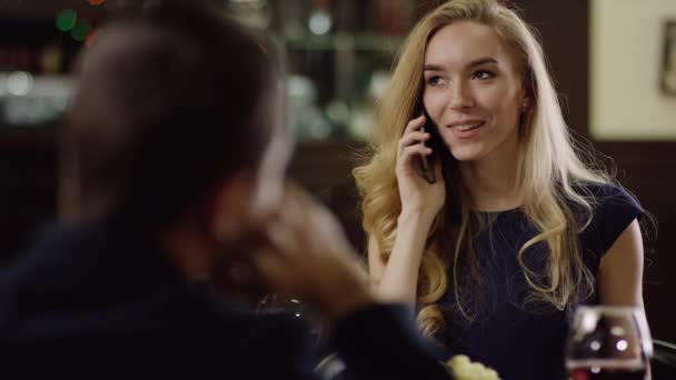 Девушка разговаривает по телефону во время свиданий в ресторане — стоковое видео