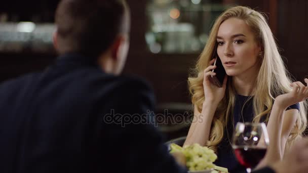 Блондинка спілкується по телефону під час побачень у кафе — стокове відео