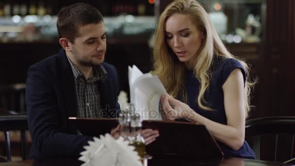 Lovers with menus at restaurant at romantic evening — Stock Video