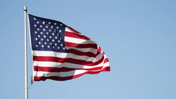 Drapeau des États-Unis agitant dans le vent contre un ciel bleu clair — Video