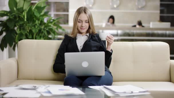 Smiling woman tourist drinking coffe and typing on laptop — Stock Video