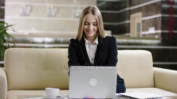 Mujer feliz turista escribiendo en el ordenador portátil en el vestíbulo del hotel — Vídeos de Stock