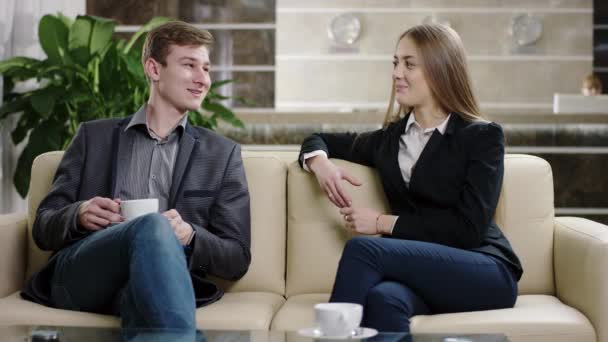 Young man and woman having a cup of coffee in lobby — Stock Video