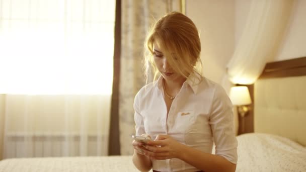 Elegante mujer hermosa mensajes de texto en el teléfono inteligente en la habitación — Vídeos de Stock