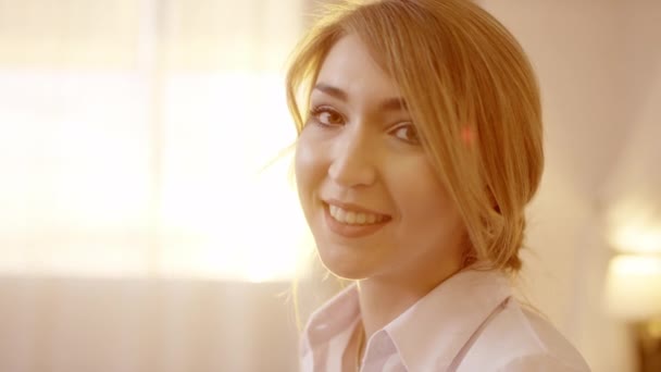 Junge schöne blonde Frau dreht den Kopf und lächelt in die Kamera — Stockvideo