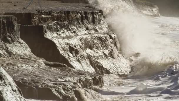 Onde oceaniche si infrangono su una spiaggia e scogliere rocciose — Video Stock